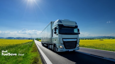 Lorry driving on a road next to a rapeseed field