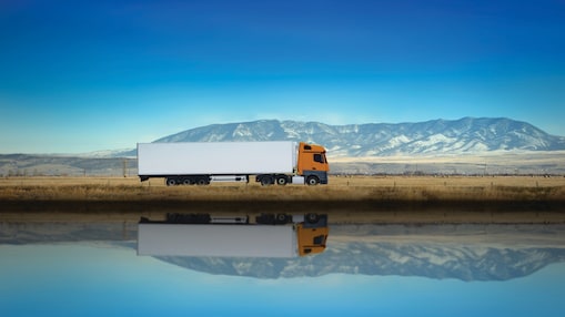Truck driving along highway on blue sky background