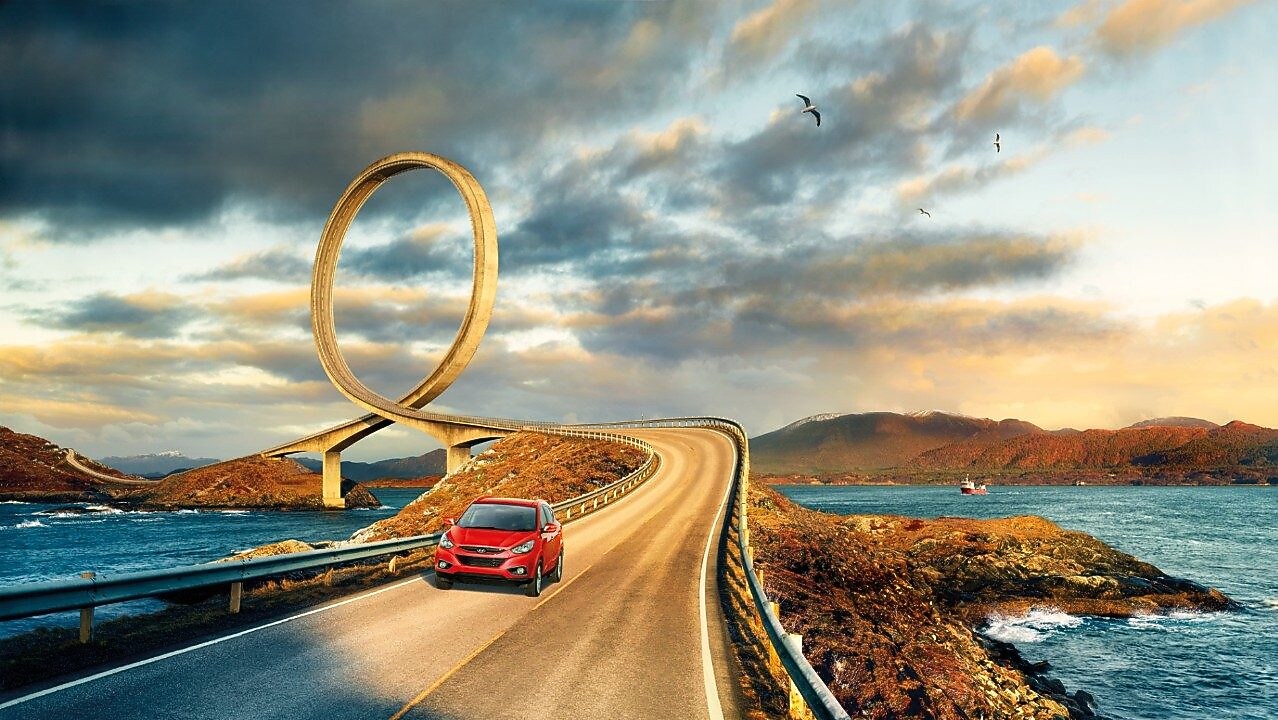 Red car driving on the road by the river