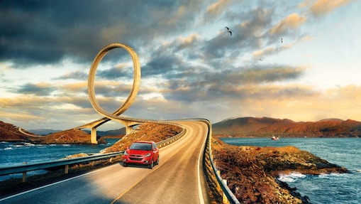 Red car driving on the road by the river