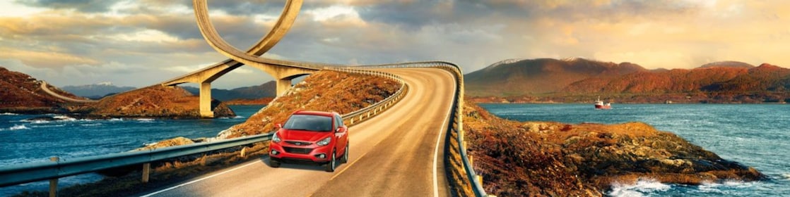 Red car driving on the road by the river