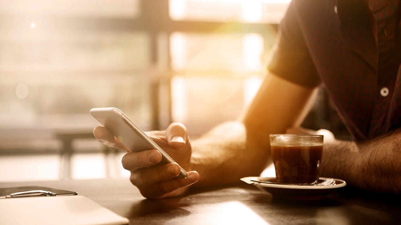 Man having a coffee looking at his smartphone