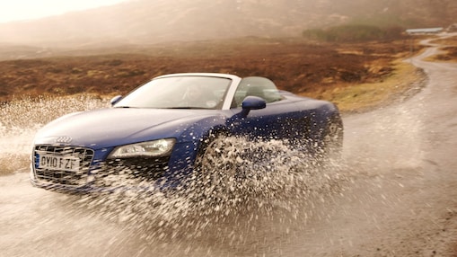 Man driving a car through a large puddle of water