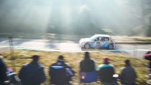 Rally car driving along a road in front of a crowd of spectators