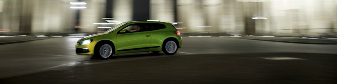 green car driving fast at night