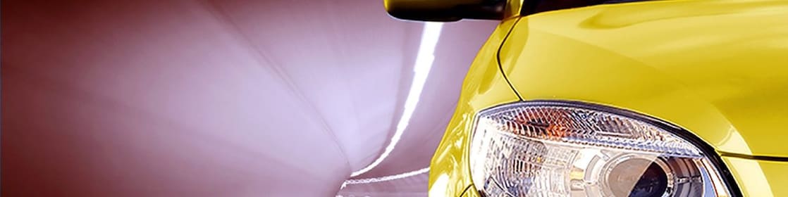 Front of a yellow car driving through a tunnel, right front light and wing mirror in view