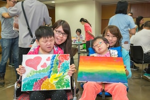 Students with special educational needs and teacher took photo with their paintings.