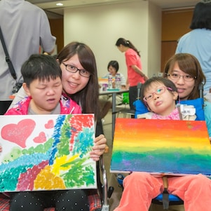Students with special educational needs and teacher took photo with their paintings.