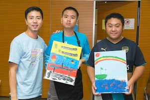 Students with special educational needs and volunteer took photo with paintings.