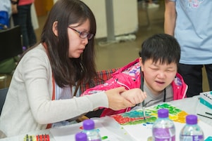 Teacher assisted student with special educational needs in art creation.