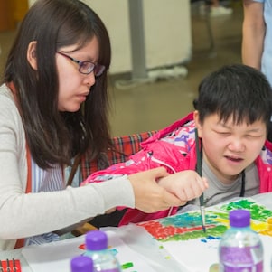 Teacher assisted student with special educational needs in art creation.