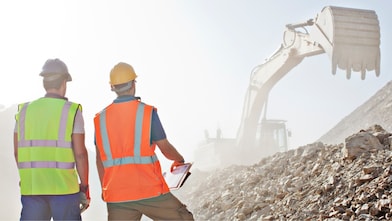 Worker standing in front of escavator