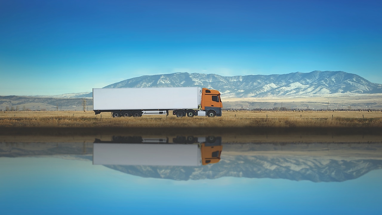 Truck driving along highway on blue sky background