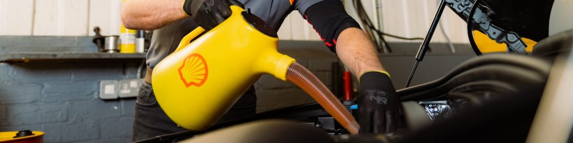 car mechanic pouring shell helix ultra oil in car